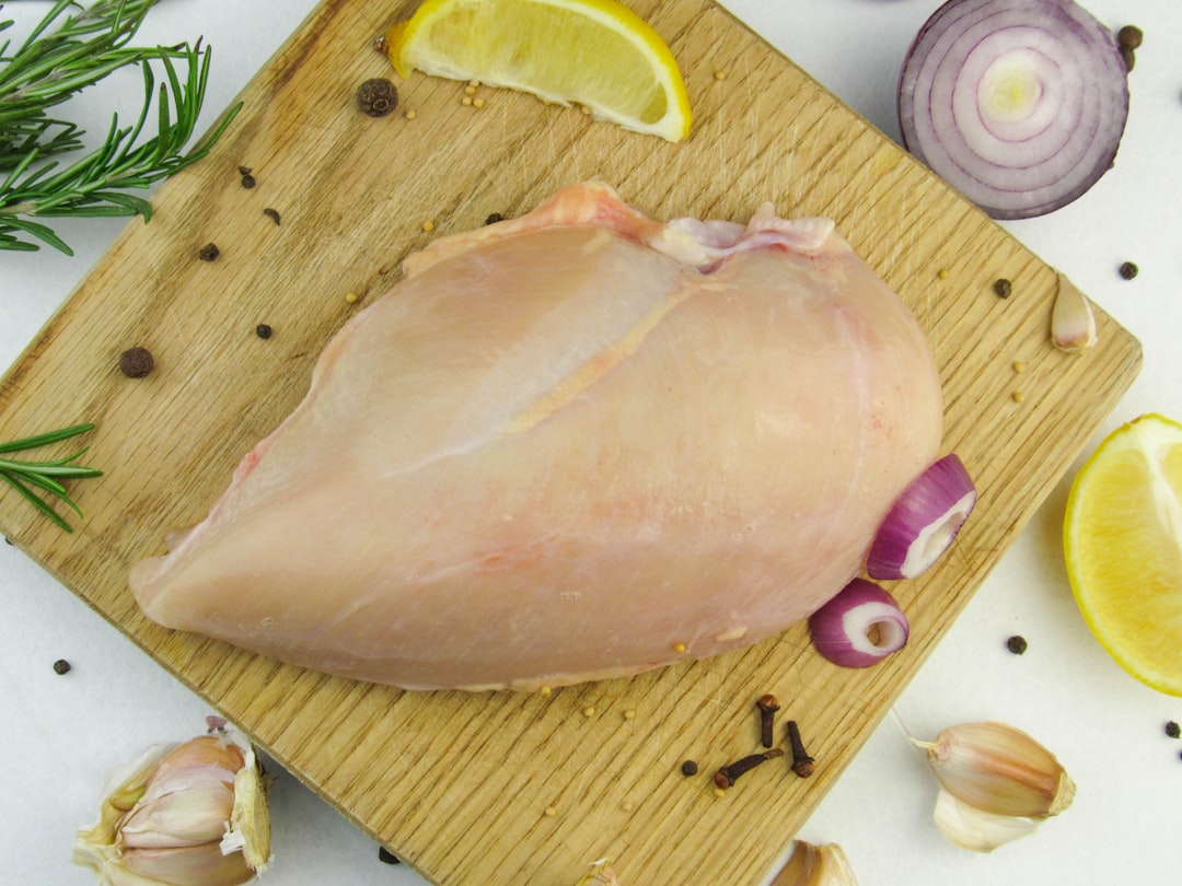 Raw chicken breast on a wooden board with garlic and lemon