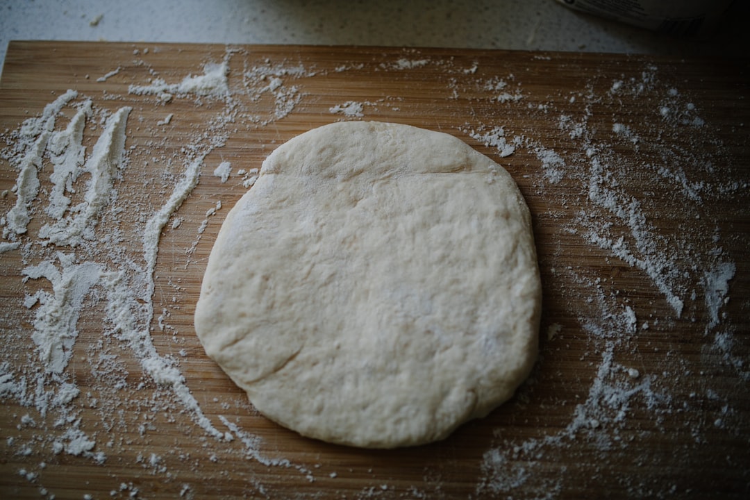 Round of pizza dough dusted with flour on a wooden board