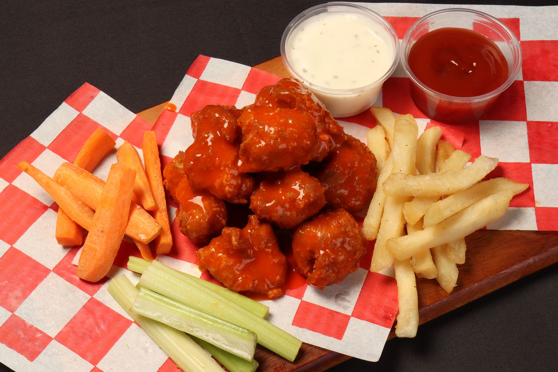 Buffalo wings with hot sauce, carrots, celery and dipping sauces on a platter