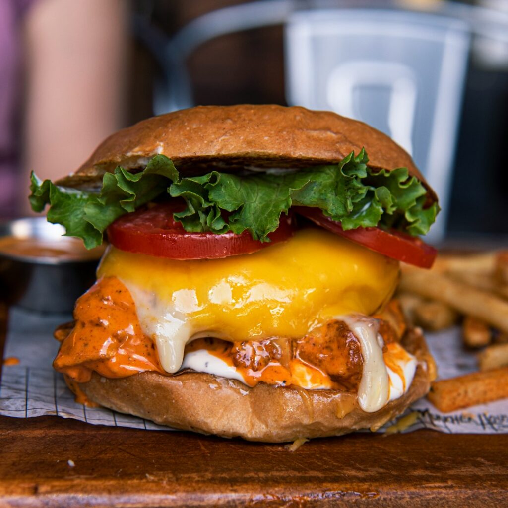 Buffalo chicken cheesesteak sandwich with melted cheese, lettuce, tomato, and buffalo sauce