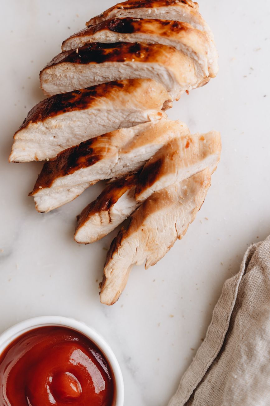 Sliced grilled chicken breast on a marble surface