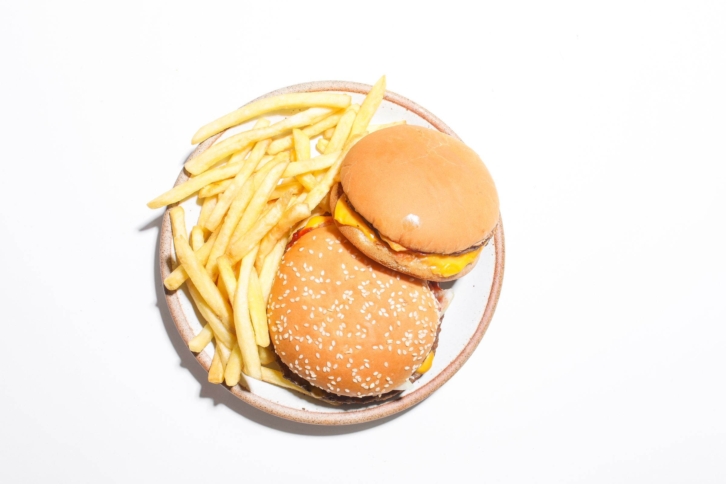 Two cheeseburgers with french fries on a white background