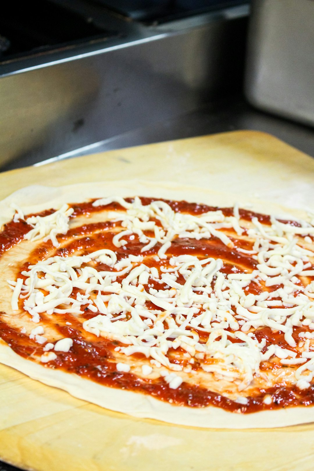 Dough topped with marinara sauce and shredded mozzarella cheese