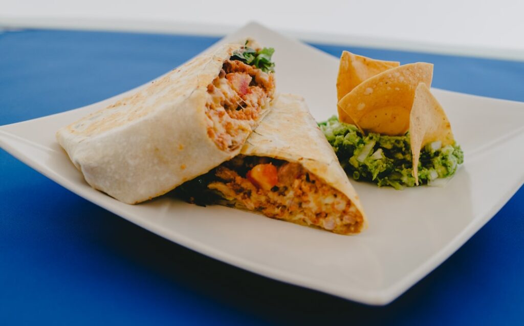 Paisa's Pizza burrito wrapped and sliced in half, showing rice, beans, and meat filling