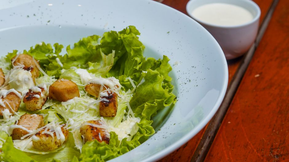 Caesar salad with croutons and shredded parmesan in a white bowl