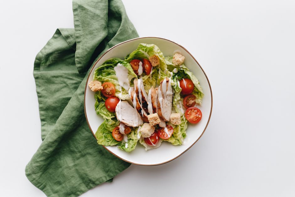 Caesar salad topped with sliced grilled chicken and cherry tomatoes