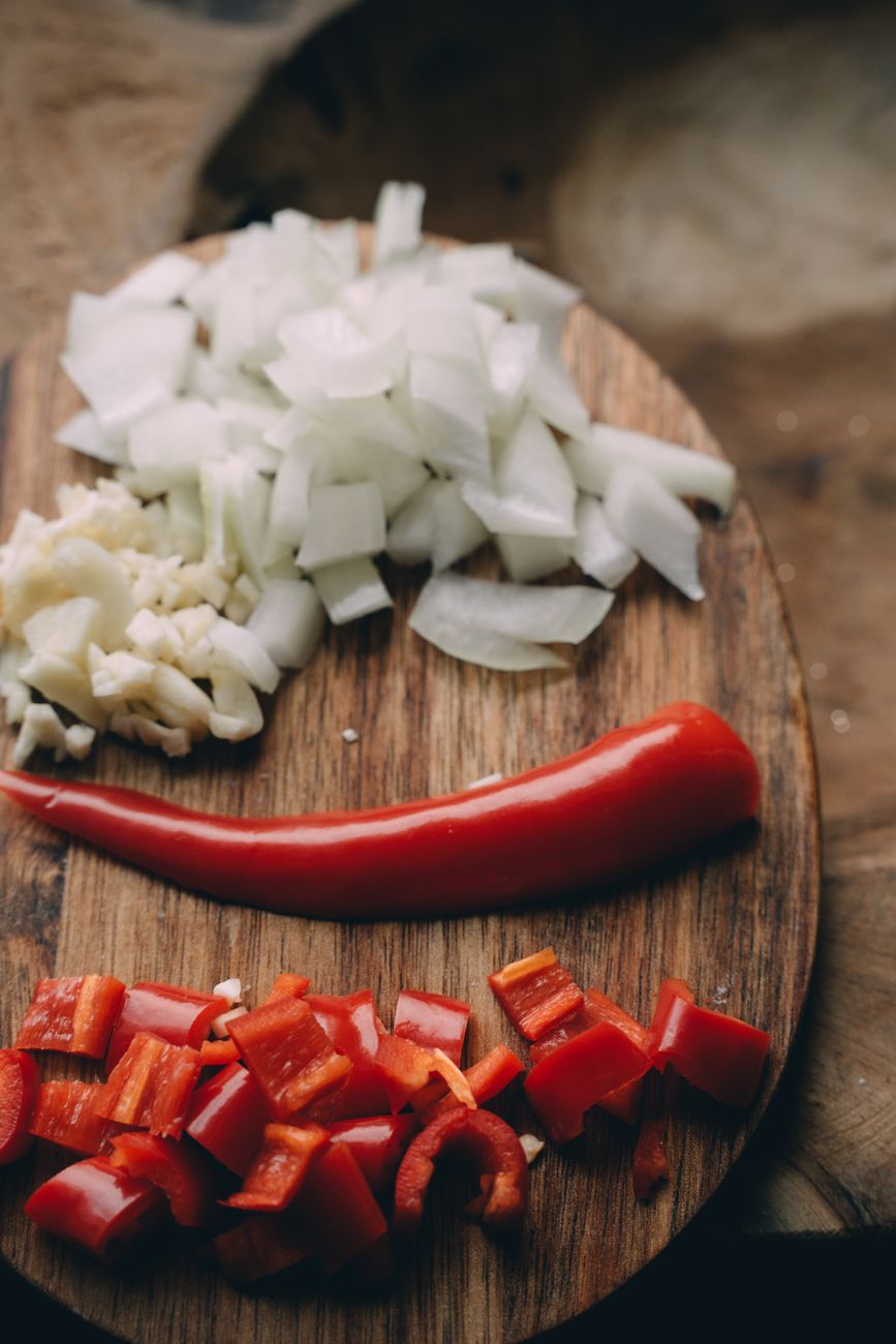 Chopped onions, garlic, and red pepper on a wooden board