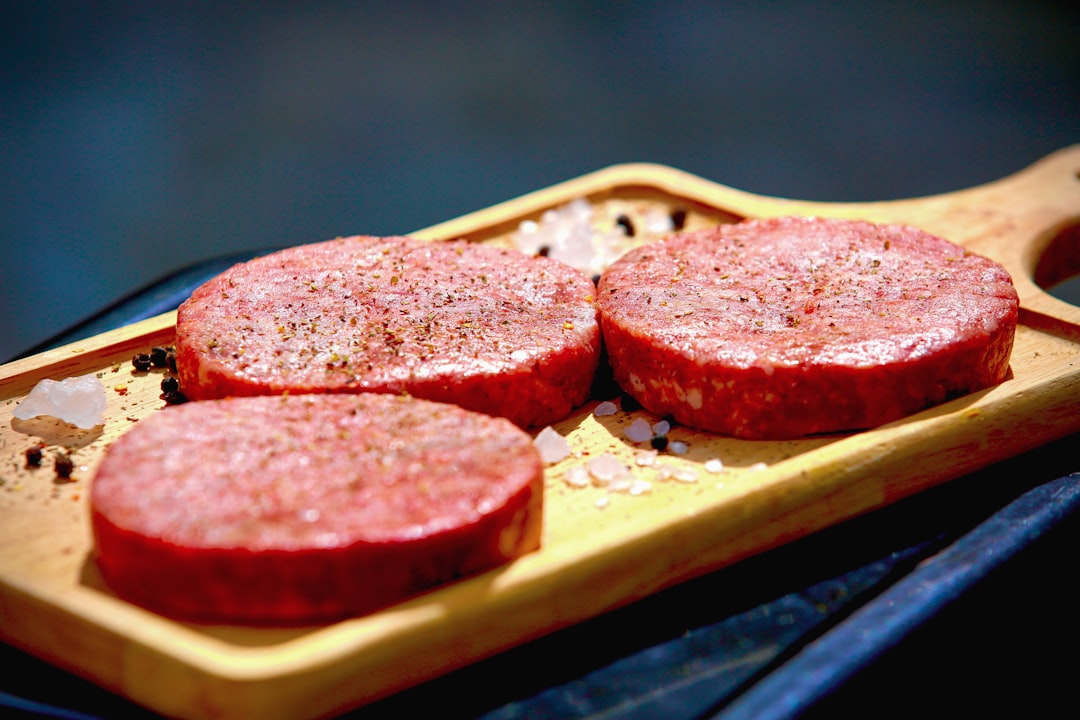 Raw beef patties on a wooden board