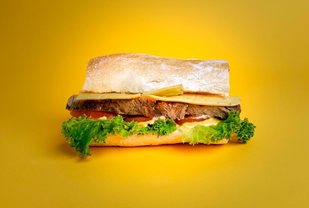 Cheeseburger hoagie sandwich with lettuce, tomato, and coleslaw