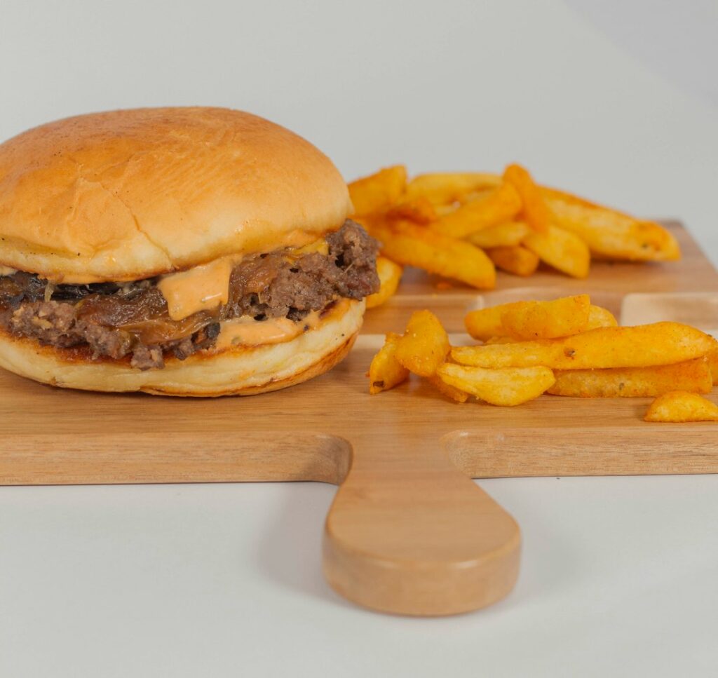 Cheesesteak sandwich with melted cheese and grilled onions on a roll, served with fries