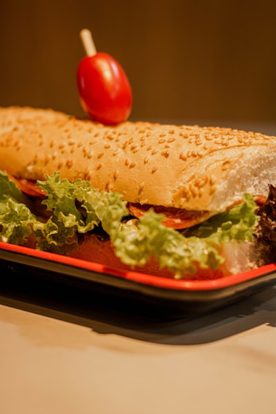 Cheesesteak hoagie sandwich with steak, melted cheese, lettuce, and tomato on a sesame roll