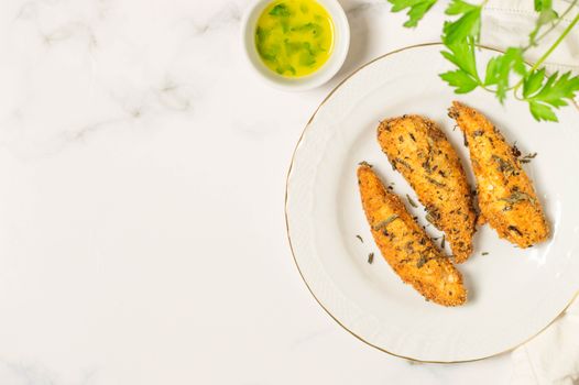 Fried chicken tenders on a white plate with dipping sauce