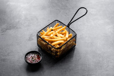 Crispy fries in a metal basket with dipping sauce
