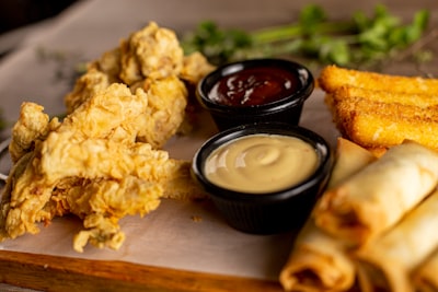Assorted fried appetizers with dipping sauces on a wooden board