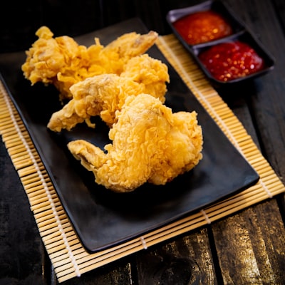 Plain fried chicken wings on a black plate with dipping sauces