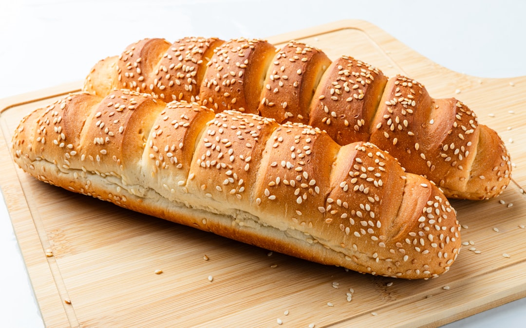 Long sesame seed bread rolls on a wooden board