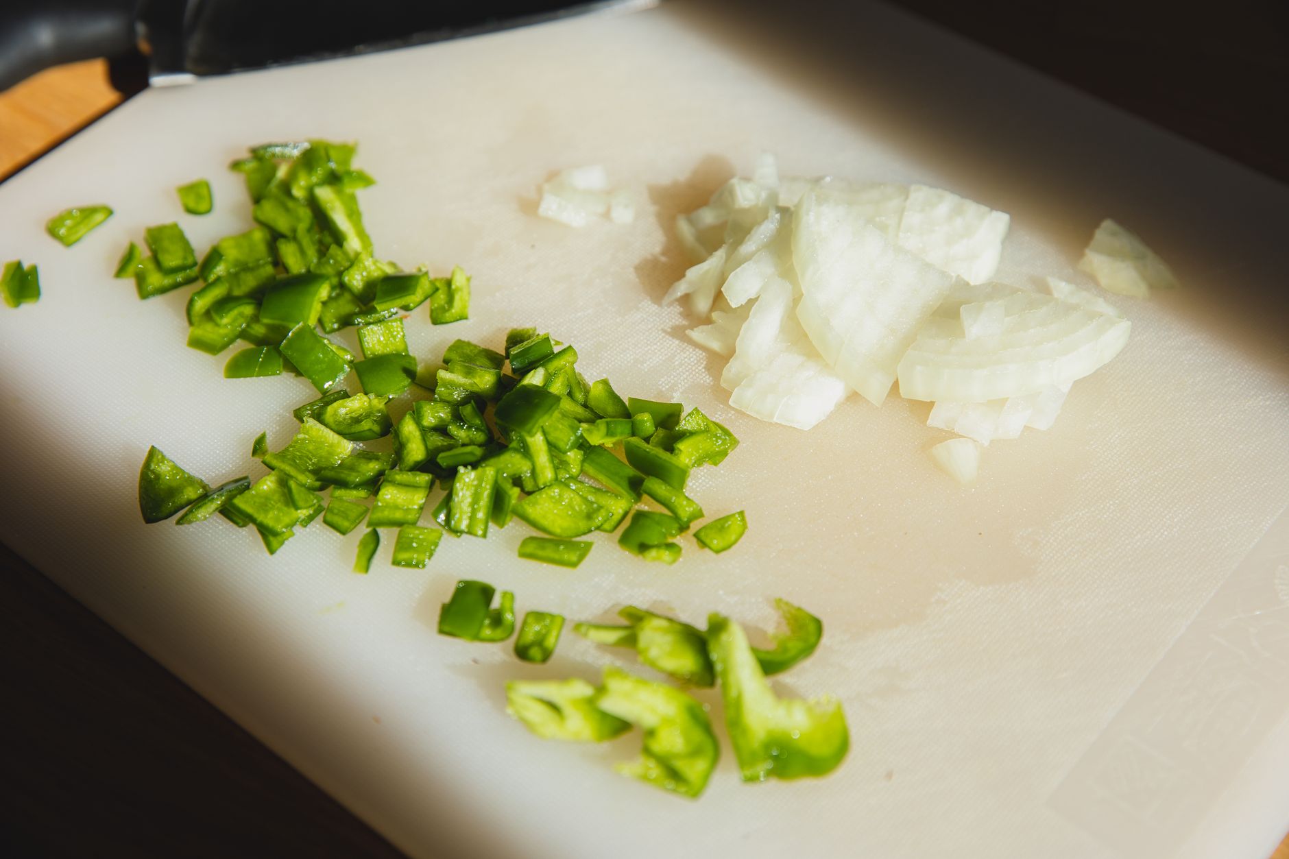 Chopped green pepper and onion on a cutting board