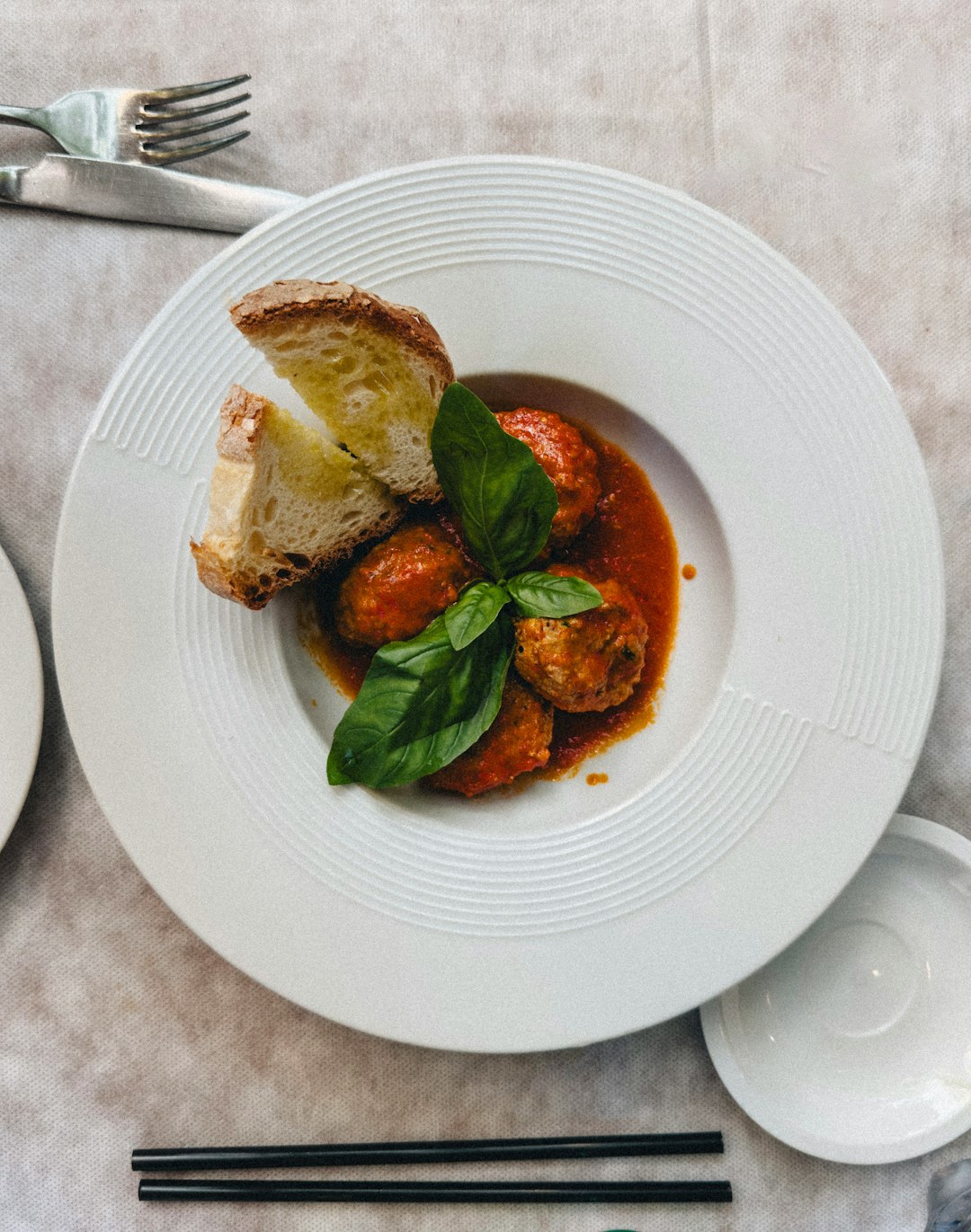 Meatballs in marinara sauce with bread and basil