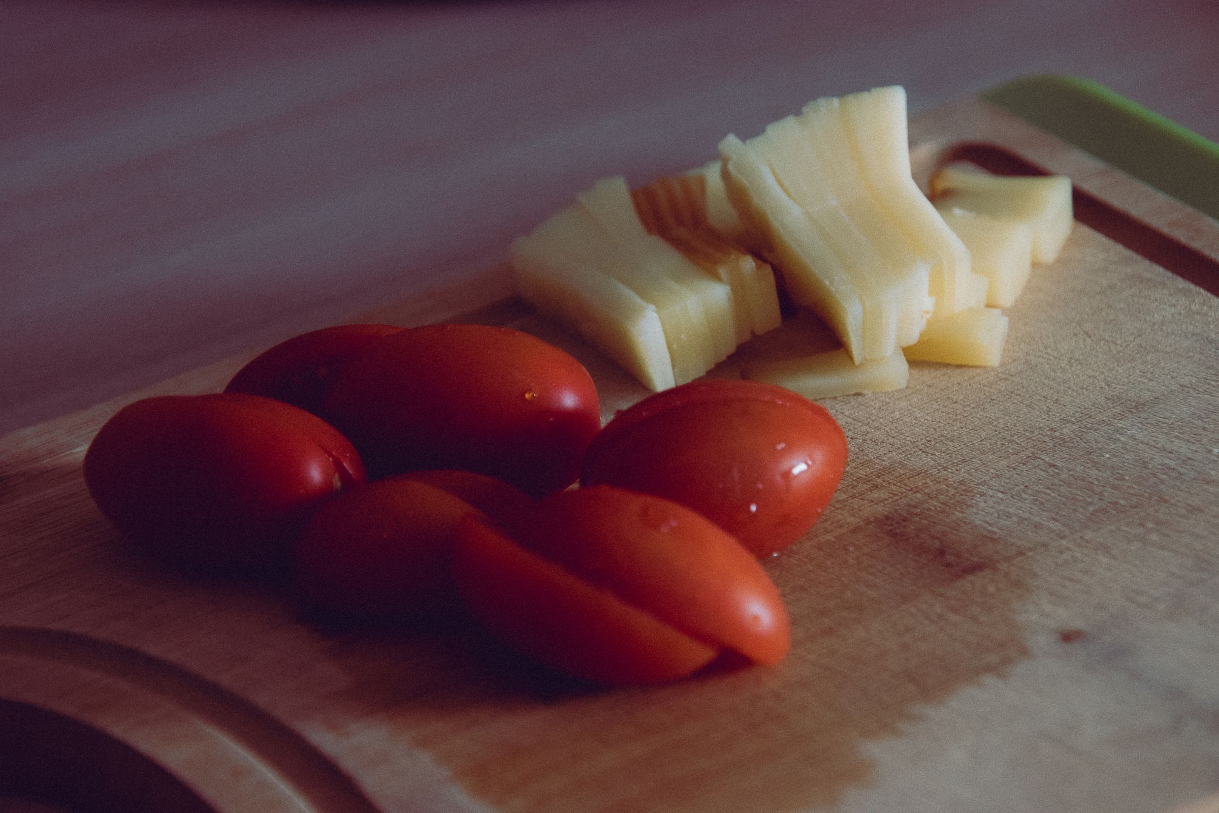 Sliced cheese and cherry tomatoes on a cutting board