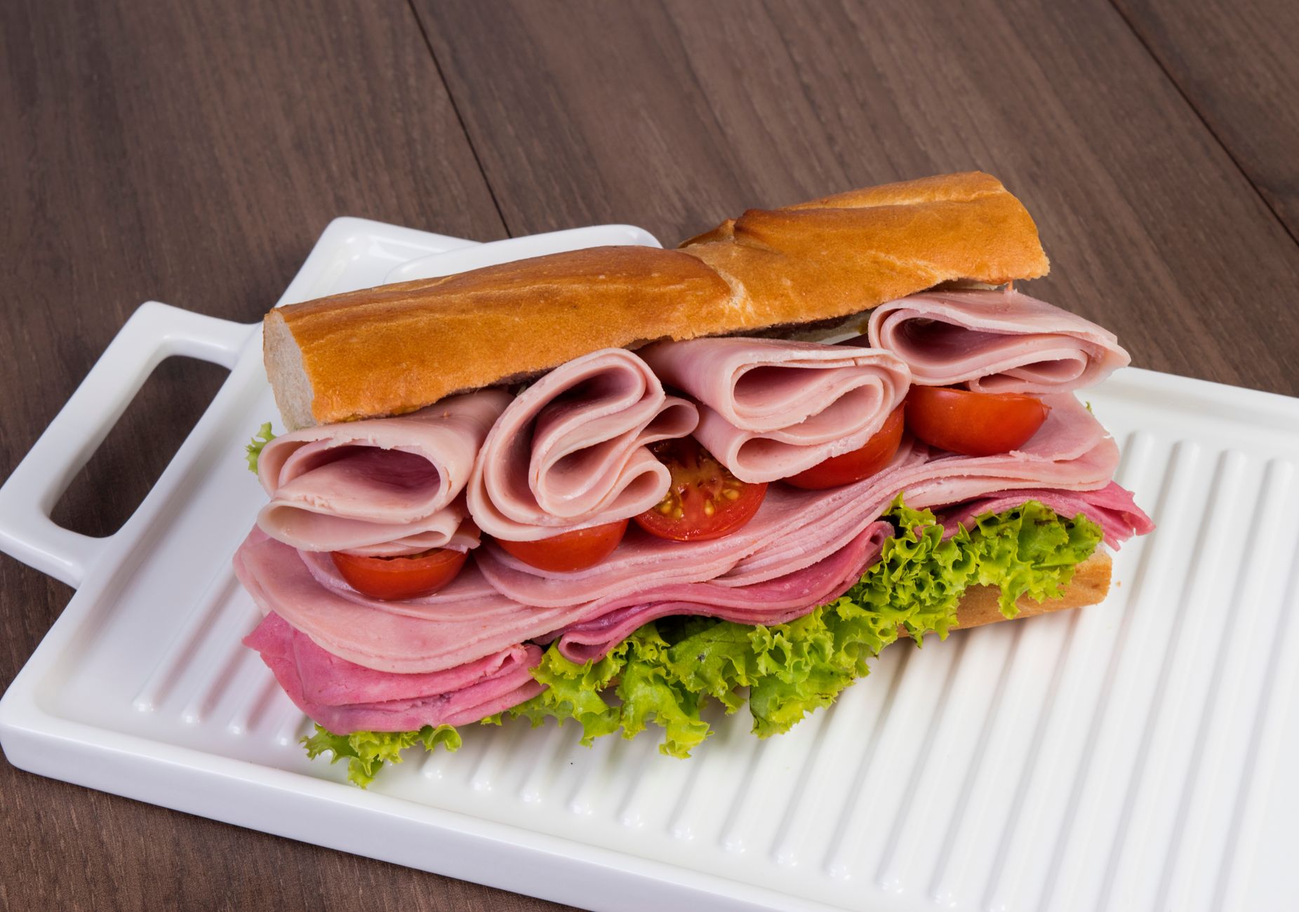 Stacked ham and salami sandwich with lettuce and tomatoes
