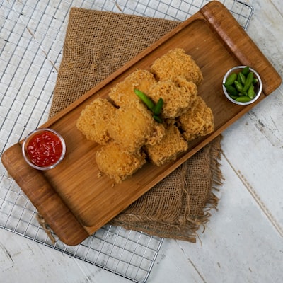 Breaded jalapeno poppers with dipping sauce on a wooden board