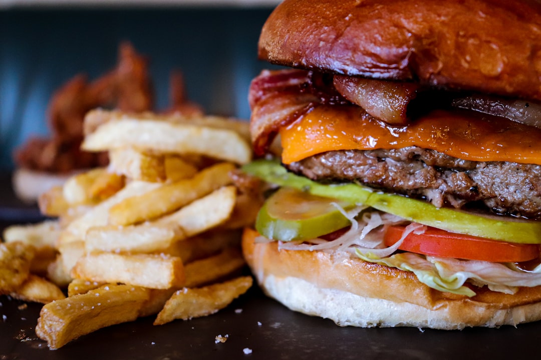 Loaded burger with melted cheddar, bacon, pickles, and tomato close up