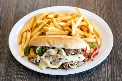 Loaded cheesesteak sandwich with melted cheese and peppers, served with fries