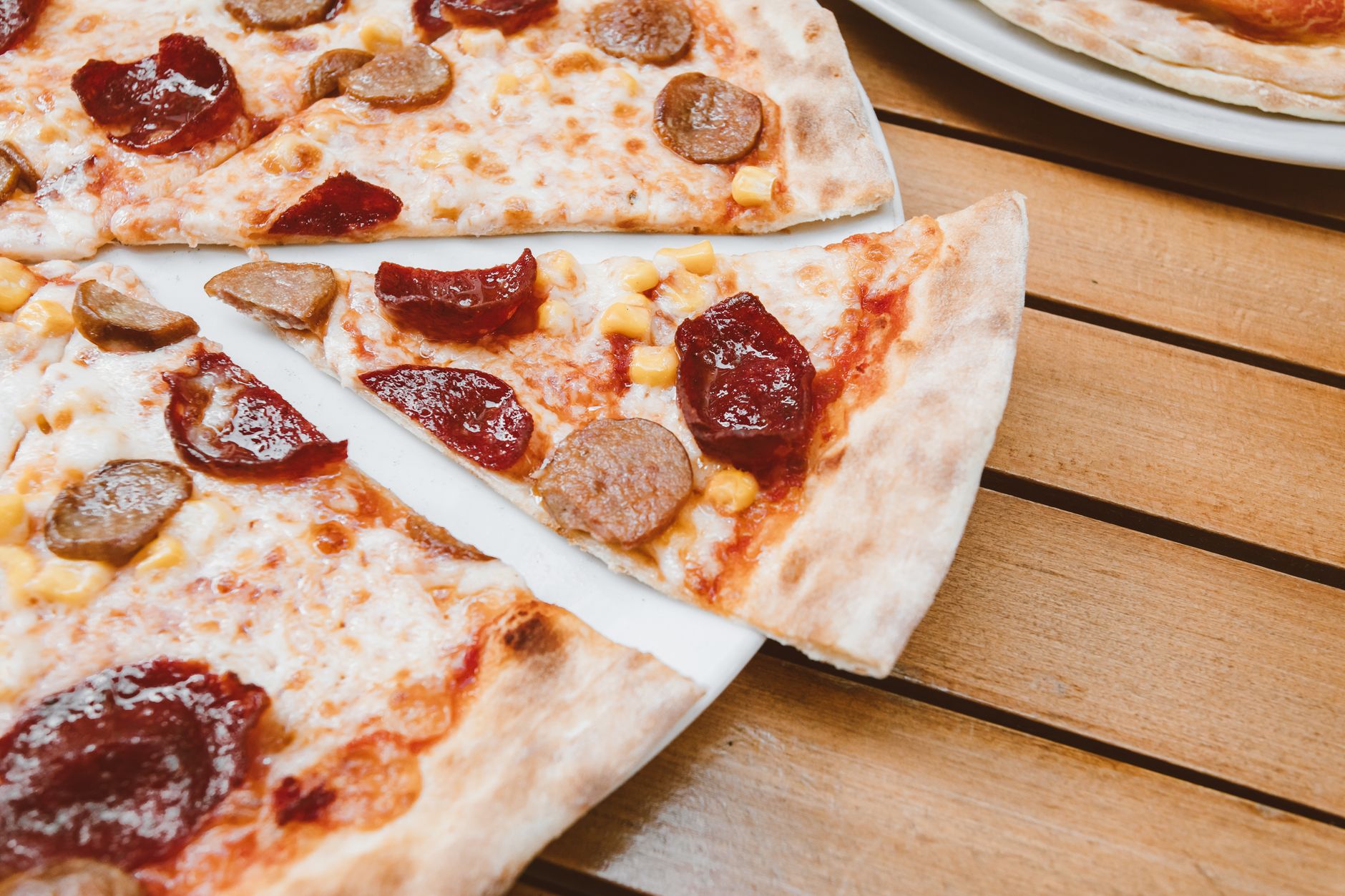 Close-up of sliced pizza topped with pepperoni and sausage
