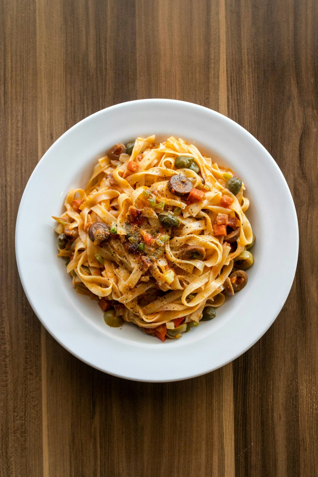 Cooked flat linguini pasta with sauce in a white bowl