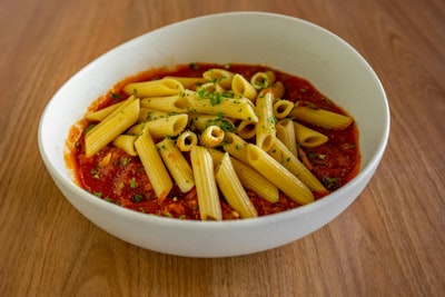 Penne pasta with marinara sauce in a white bowl