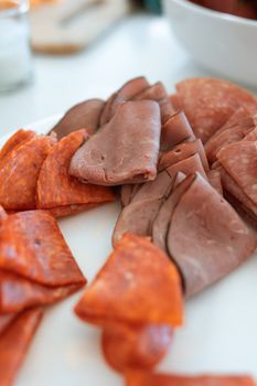 Sliced pepperoni and deli meat on a white plate