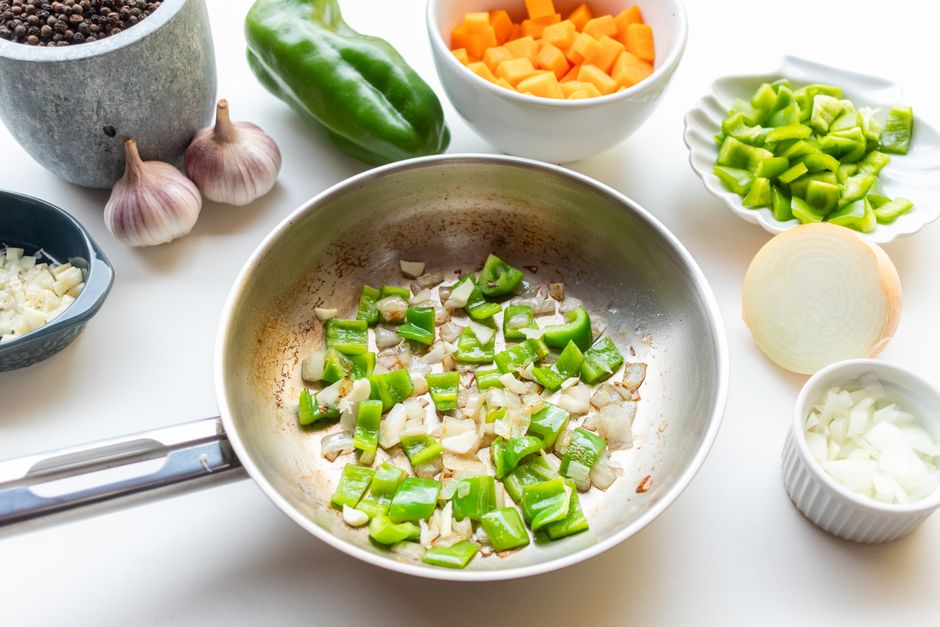 Sauteed onions and green peppers cooking in a pan
