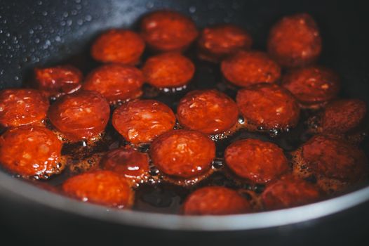 Sliced chorizo sizzling in a pan