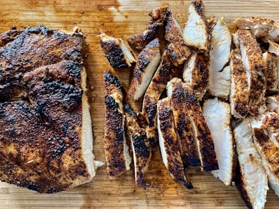 Sliced grilled chicken on a wooden cutting board