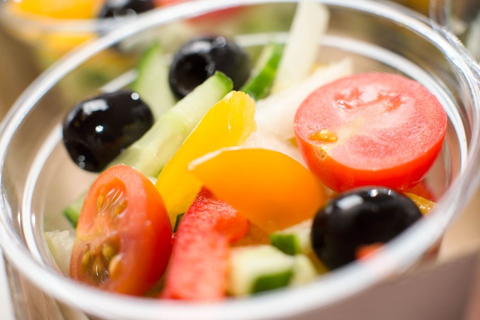 Sliced tomatoes, cucumber, and black olives in a glass bowl