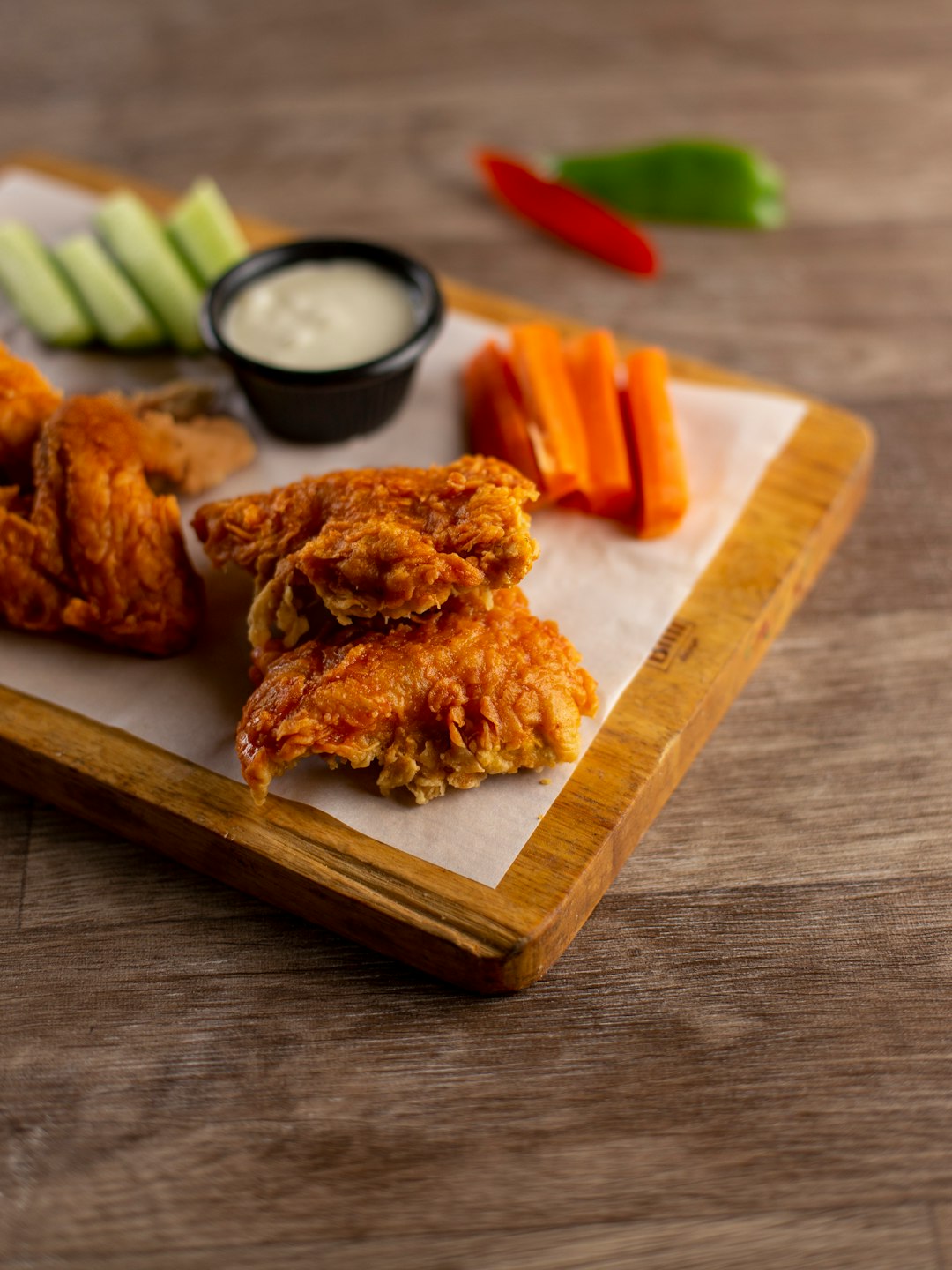 Buffalo wings tossed in sauce with celery and carrots on a board