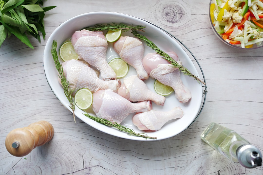 Raw chicken drumsticks with lime on a tray