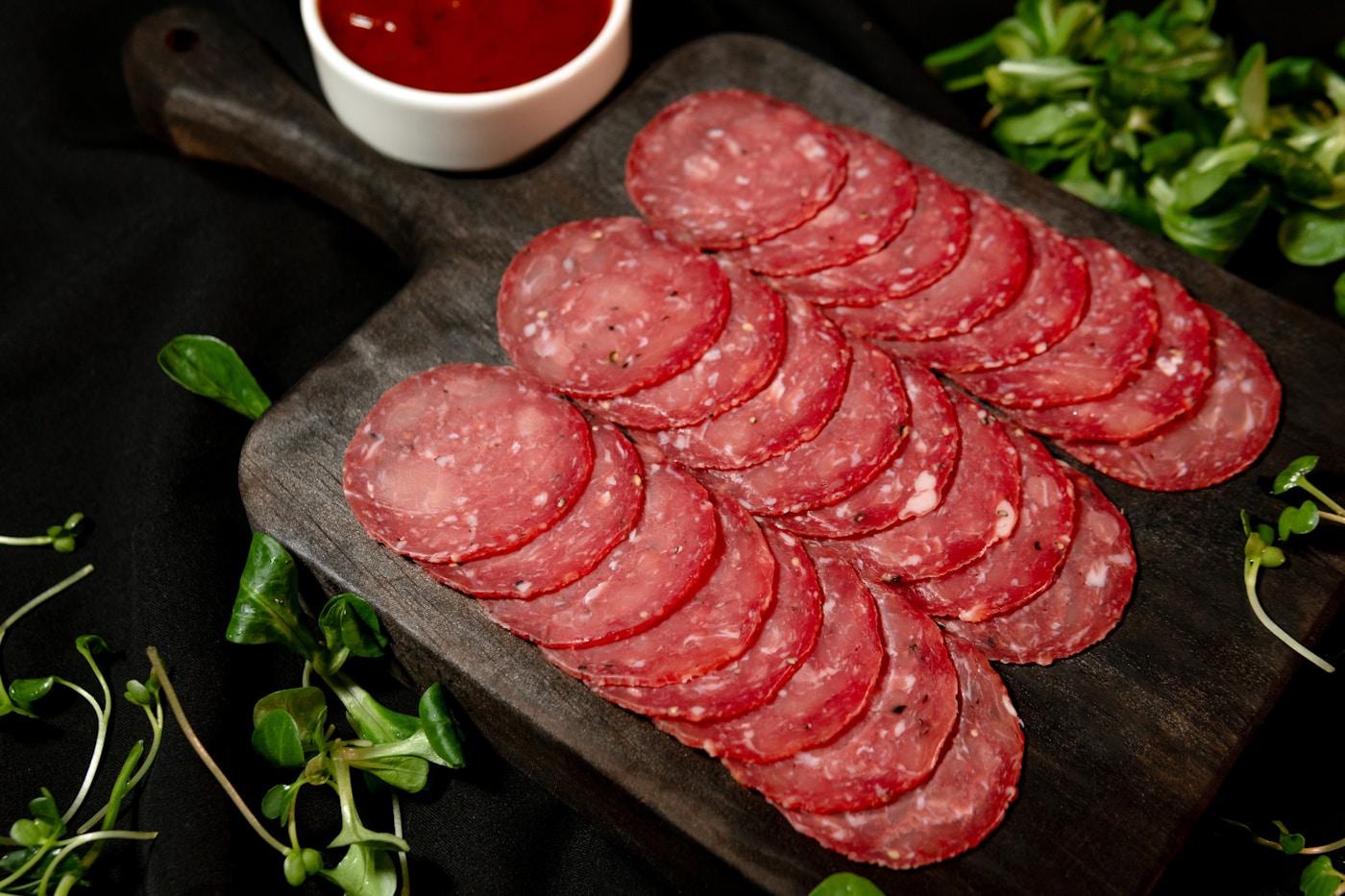Thinly sliced pepperoni arranged on a wooden cutting board