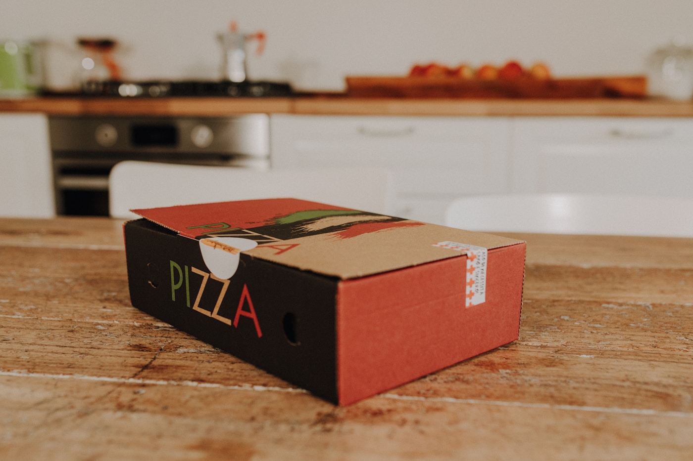 Closed pizza delivery box sitting on a wooden kitchen table