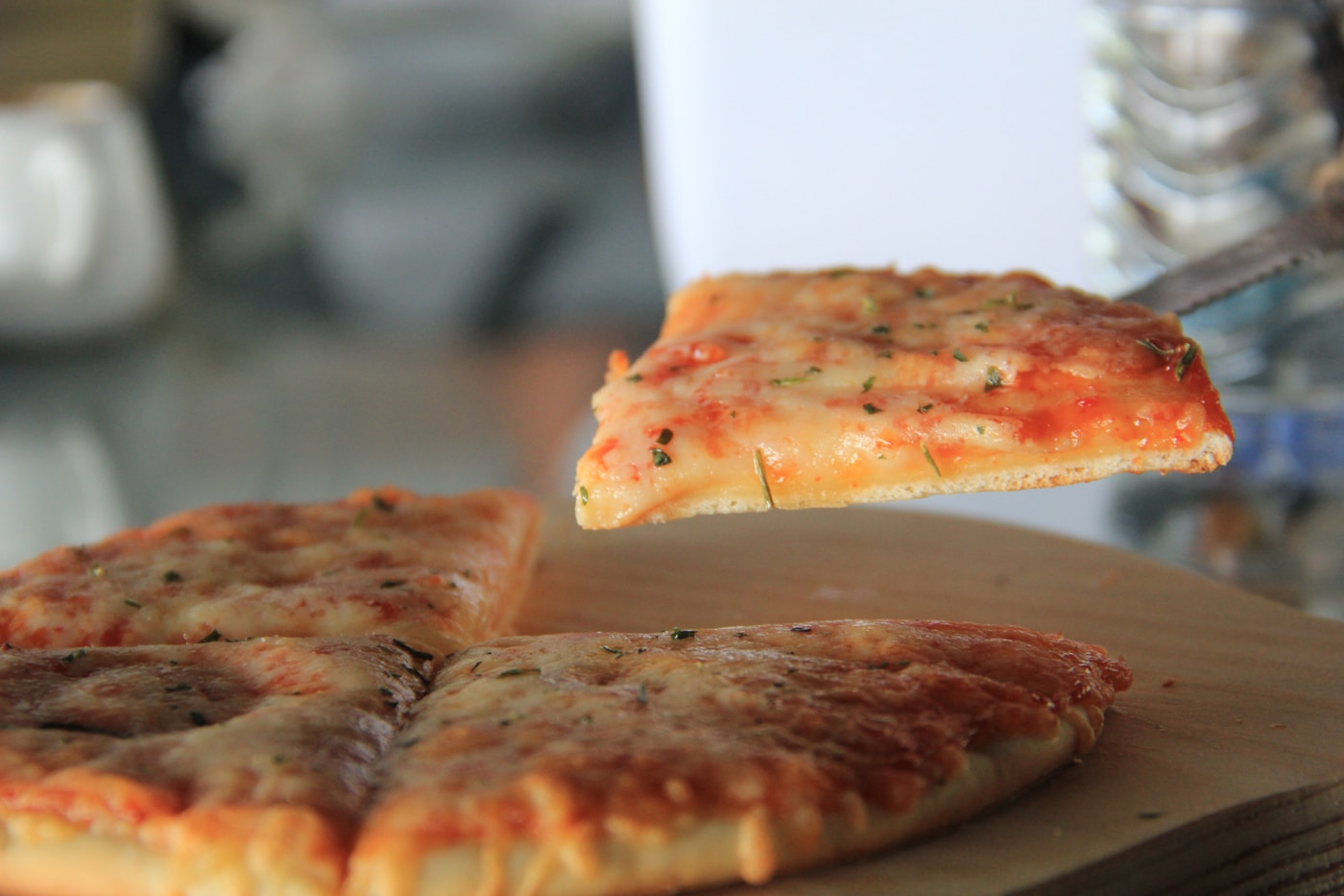 Slice of pizza being lifted with a server, showing the crispy crust edge