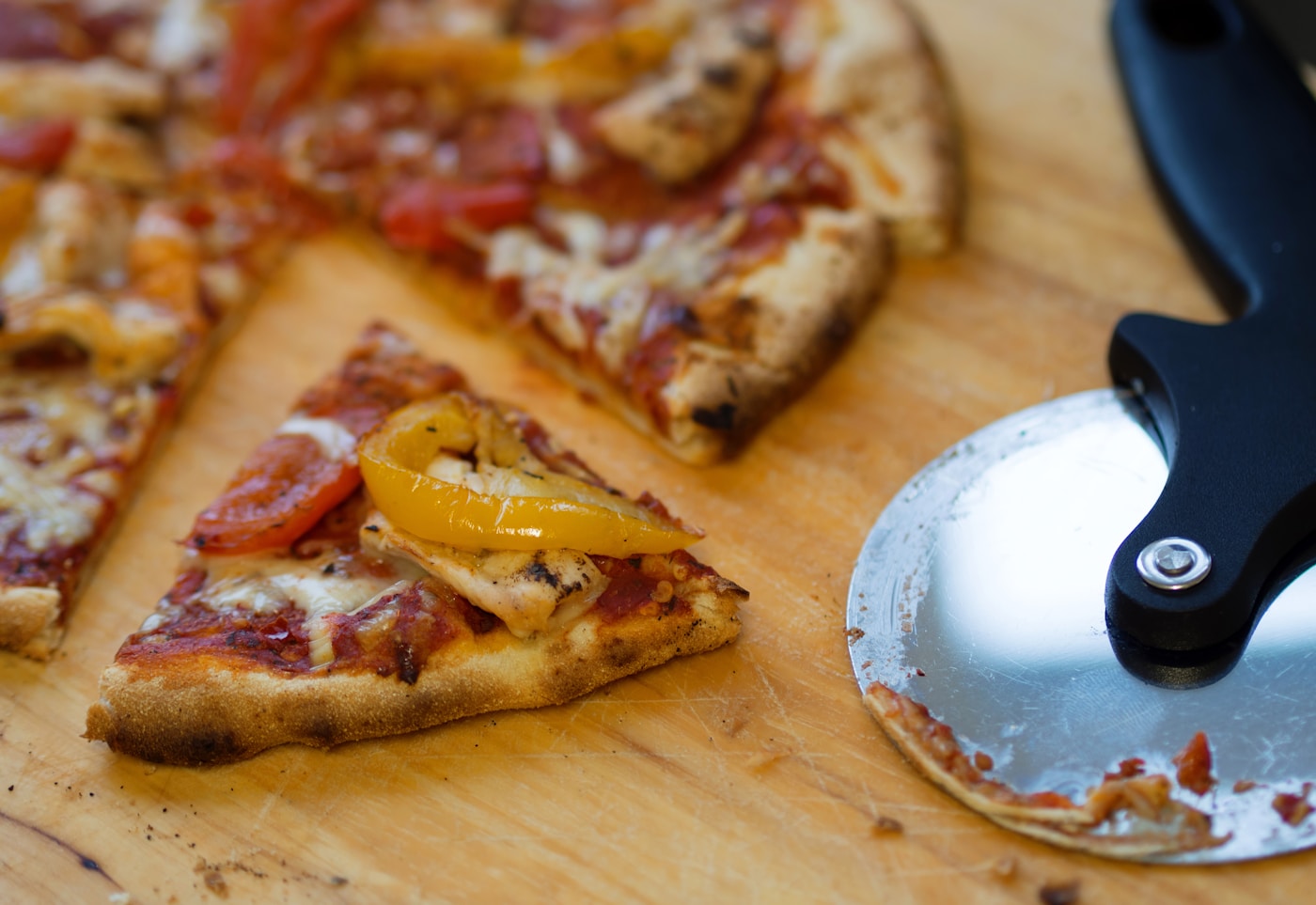Metal pizza wheel cutter next to a freshly sliced pizza