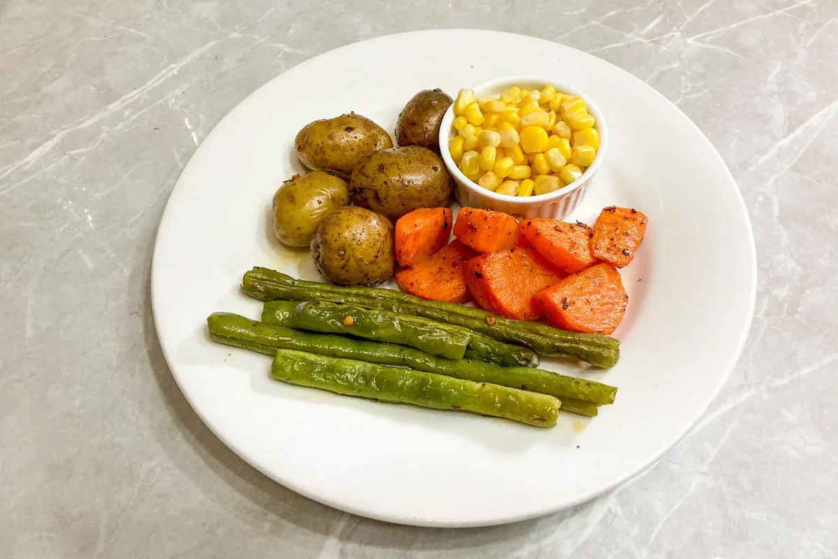 A plate of roasted potatoes, carrots and corn