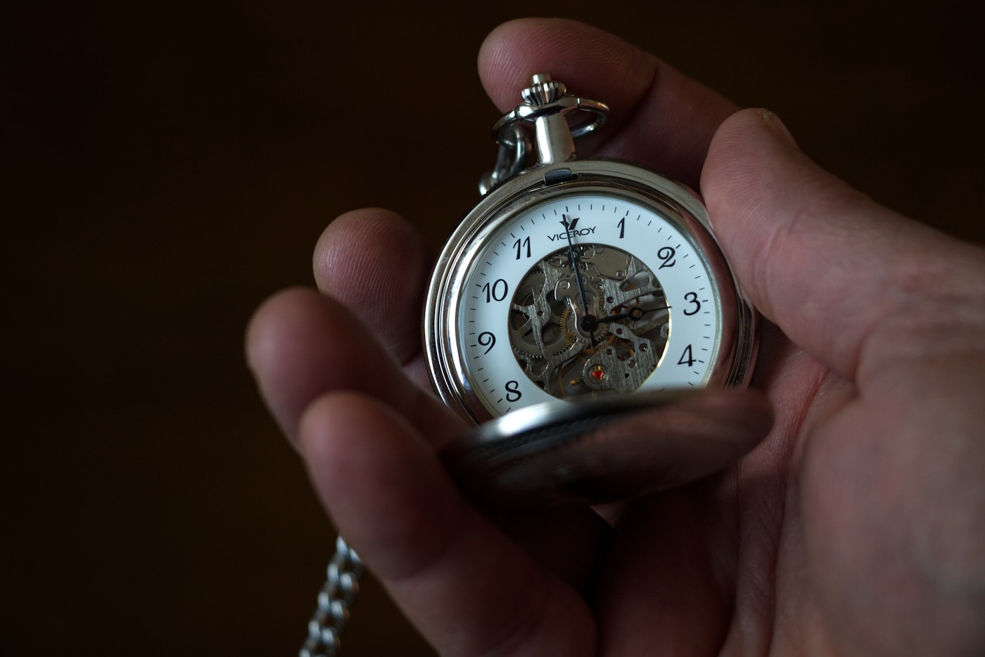 Hand holding a pocket watch, representing timing and speed