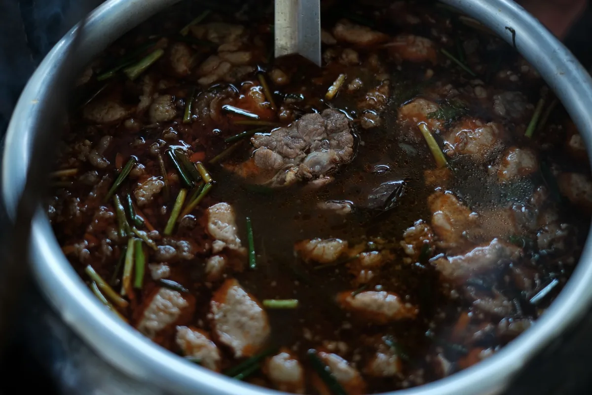 Beef stew simmering with herbs and spices in a metal pot