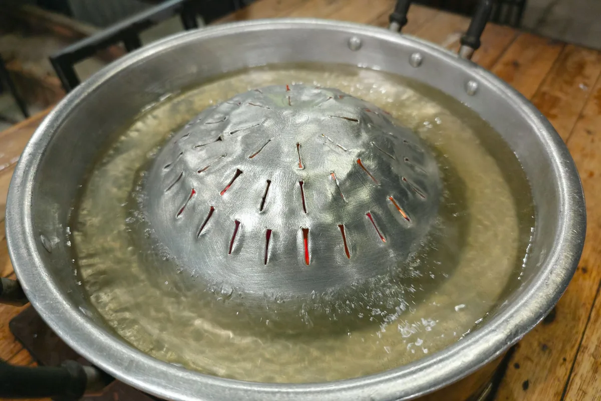 Steam rising from a metal pot on a stove