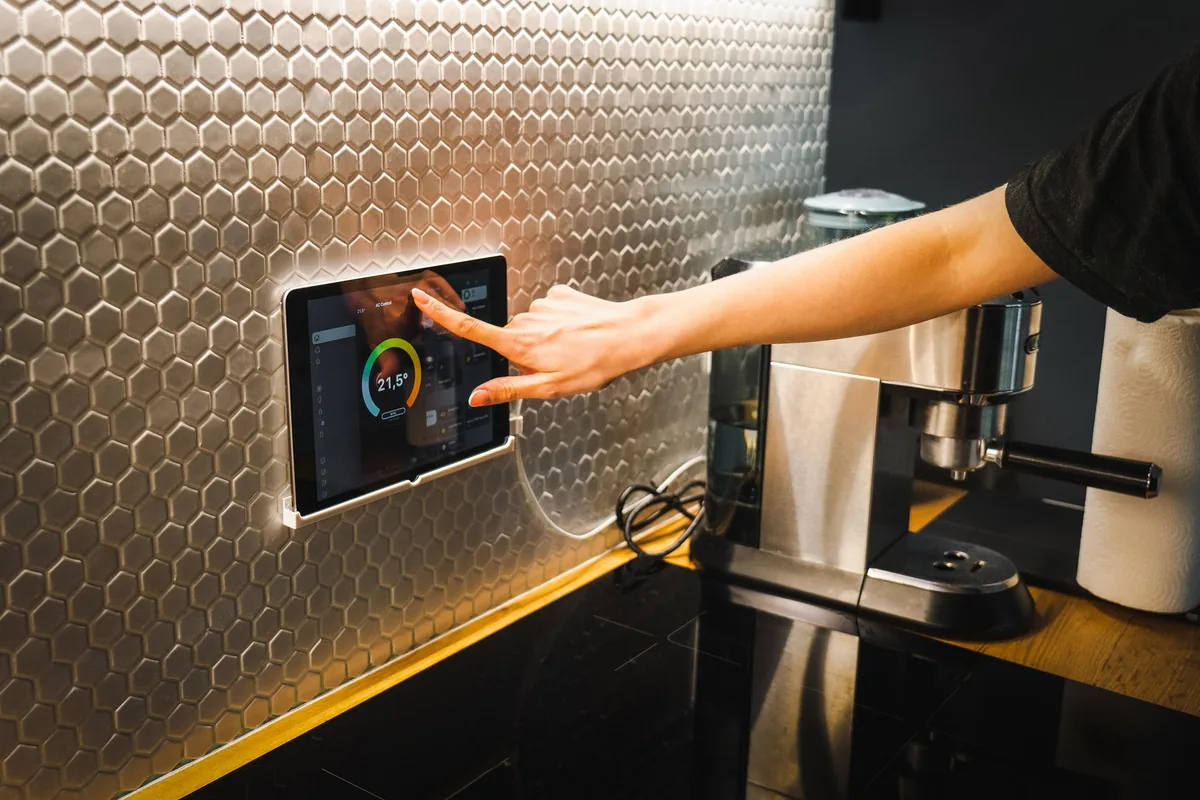Hand using a tablet to control a modern kitchen