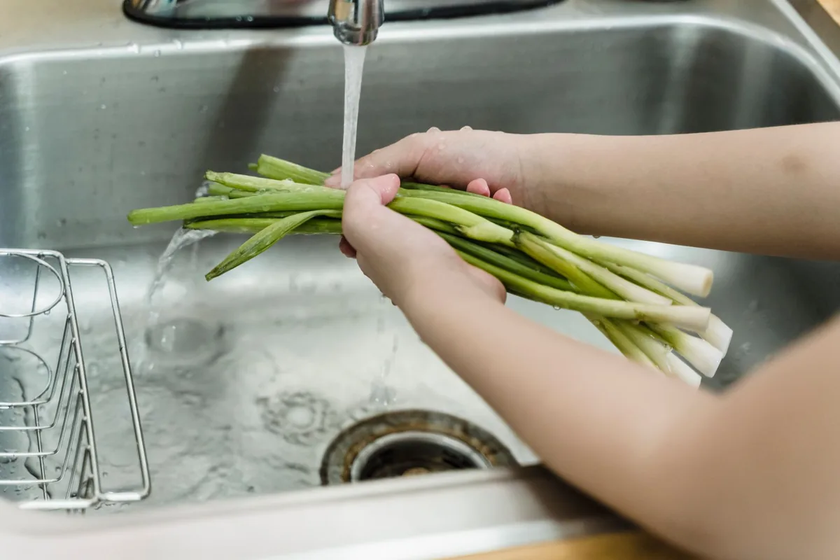 Rinsing greens under a tap