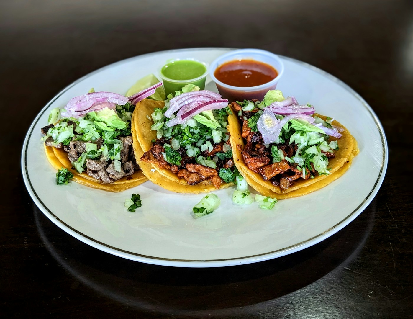 Three shredded meat tacos topped with pickled red onion and cilantro