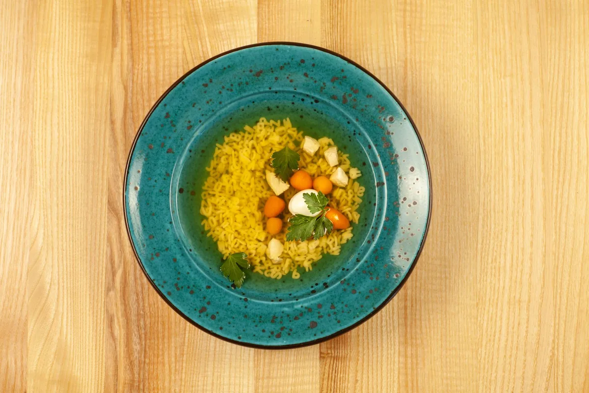 Chicken soup with fresh greens in a blue bowl