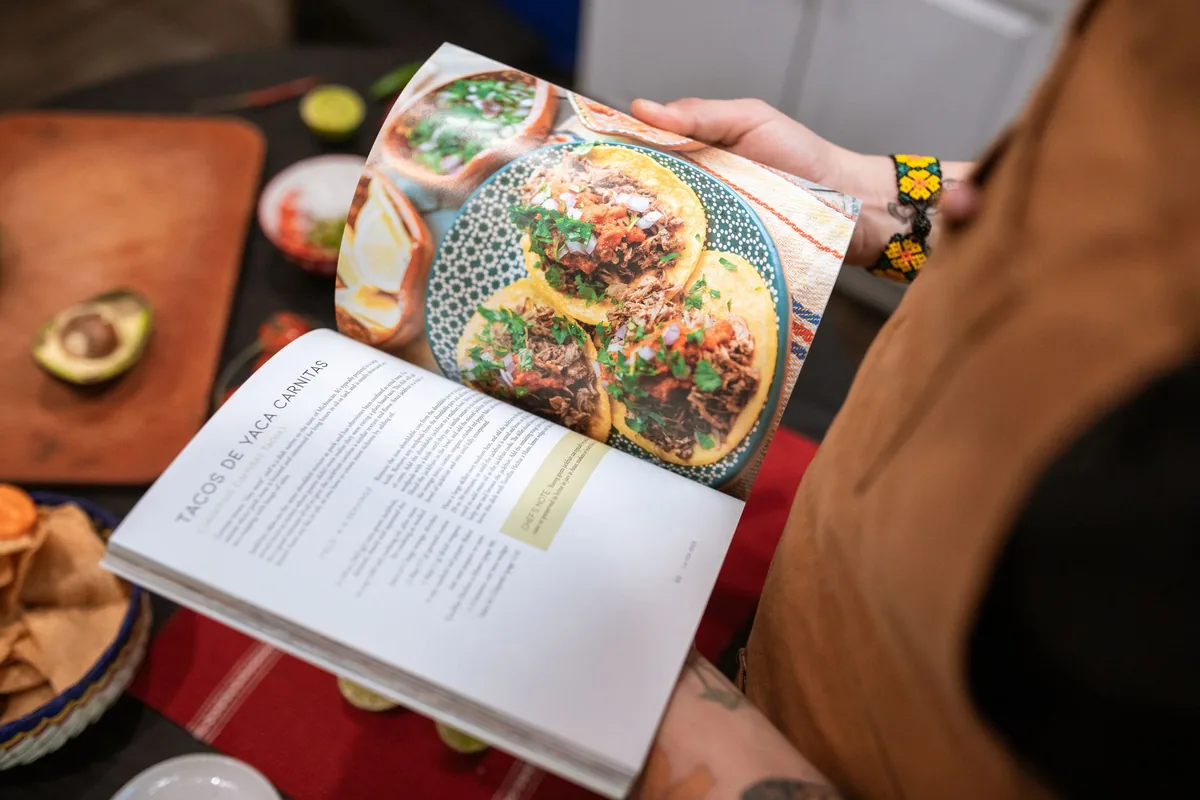 Person holding a cookbook open to a recipe page